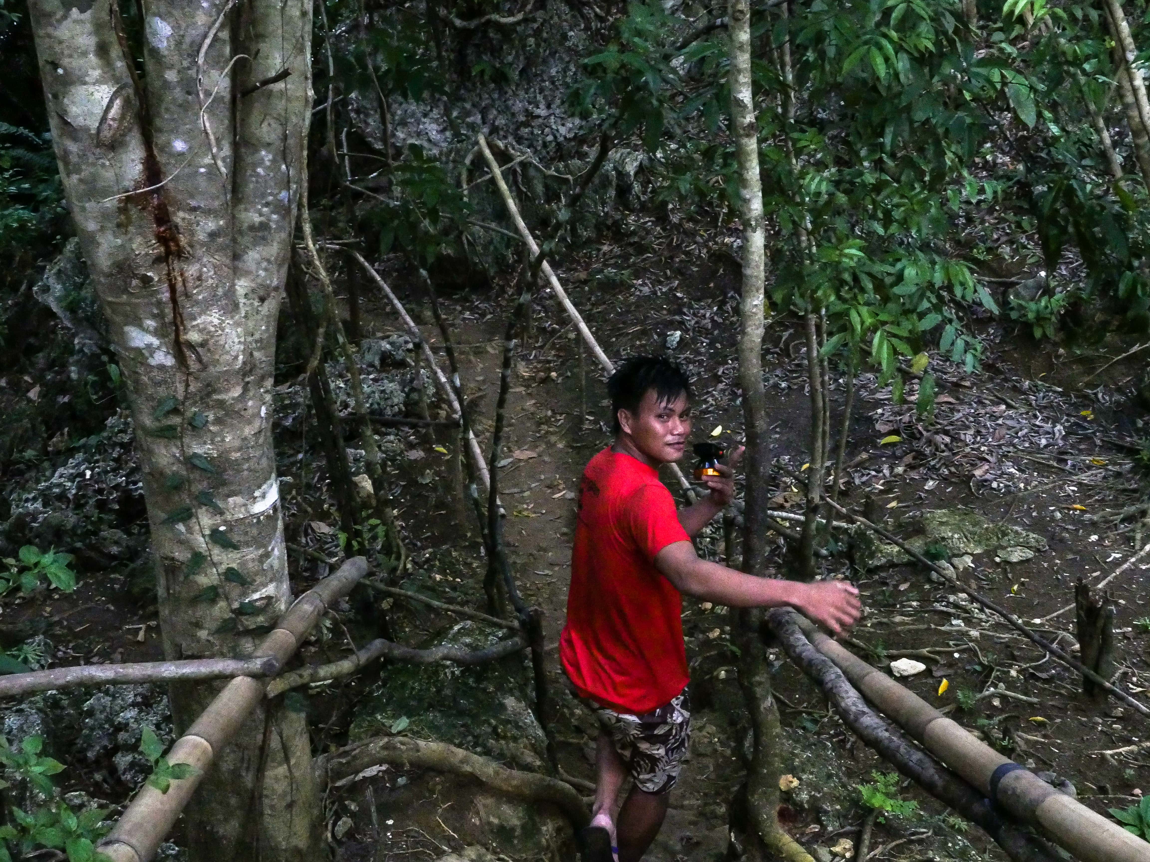 guide leading visitor towards entrance of tayangban cave in siargao philippines